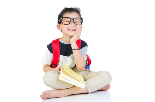 Asian preschool boy with schoolbag and books sitting on the floor