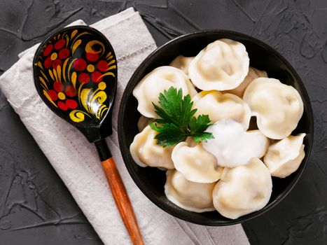 Traditional russian pelmeni, ravioli, dumplings with meat on black concrete background. Top view or flat lay. Russian food and russian kitchen concept.
