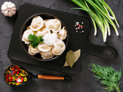 Traditional russian pelmeni, ravioli, dumplings with meat on black concrete background. Top view or flat lay. Russian food and russian kitchen concept.