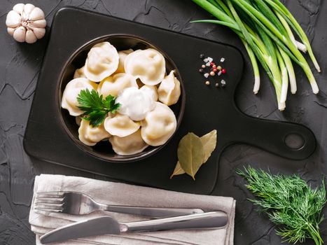 Traditional russian pelmeni, ravioli, dumplings with meat on black concrete background. Top view or flat lay. Russian food and russian kitchen concept.