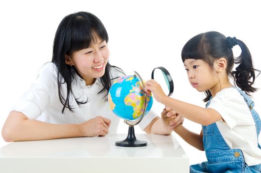 Asian girl and her mother looking at the globe at study room