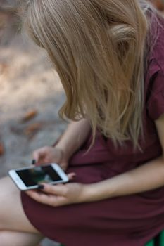 Young attractive woman at the park, she is texting with her smartphone