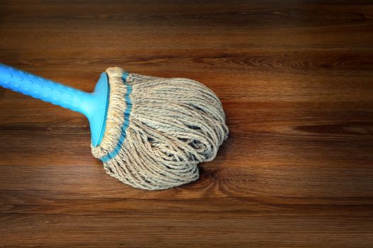 closeup of mop on the floor, cleaning interior wooden surface