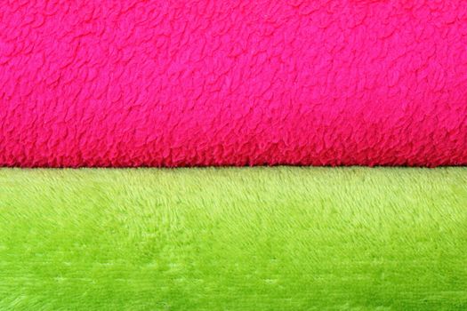 colorful background of textured blankets, detail of stack with green and pink material