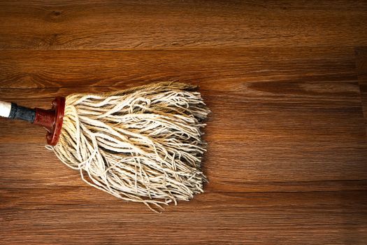 detail of mop cleaning on wood floor, brown parquet