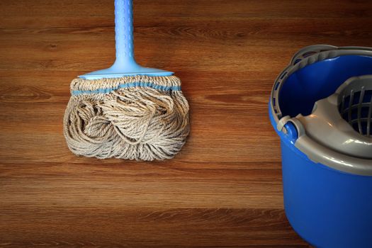 cleaning equipment on wooden floor, mop and blue bucket