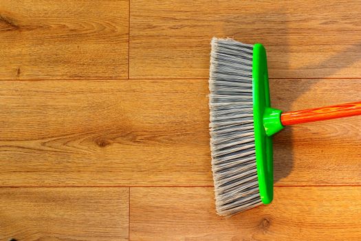 cleaning brown wooden floor with a broom