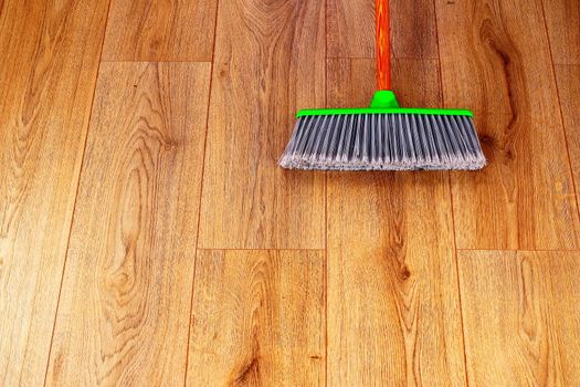 cleaning the interior wooden floor with green plastic broom