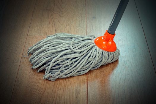 detail of wooden floor cleaning with orange mop