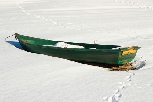 green abandoned boat on lake shore in winter