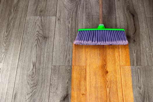 sweeping out wooden parquet with green plastic broom