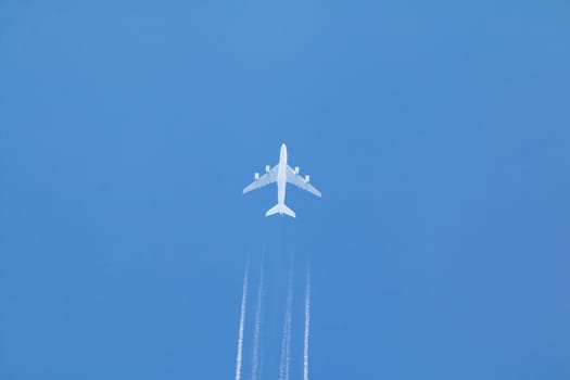 Passenger jet airplane with contrail or vapour trail against clear blue sky.