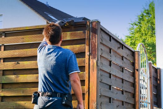 Man with artificial heart strokes a wood fence in the garden.