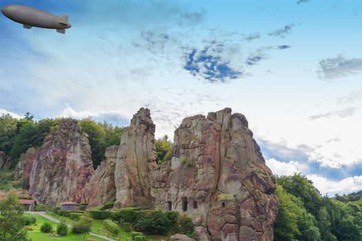 Airship, zeppelin flying over the Externsteine, taking photo  taken in front of  dramatic sky. Markant sandstone rock formation in the Teutoburg Forest, Germany, North Rhine Westphalia.