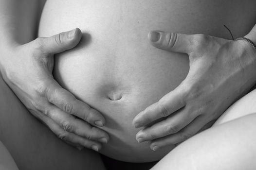 Black and white belly of pregnant woman closeup, nine month