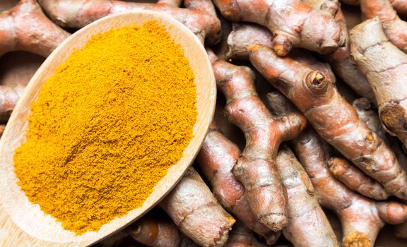 Closeup top view turmeric powder and turmeric roots on old wood background, spa beauty skin care concept