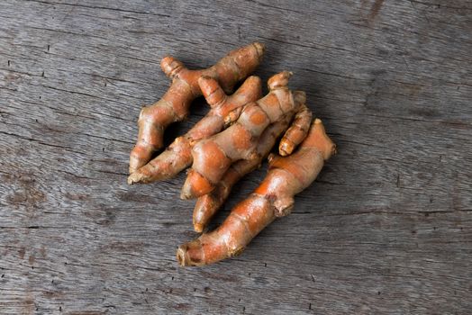 Fresh turmeric roots on wood background, herb and healthy care concept