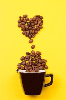 A cup of coffee and heart of the beans on yellow background