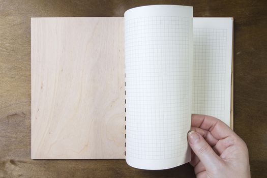 Hands flipping page notebooks on a wooden table