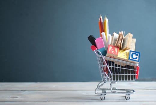 Shopping cart filled with stationery next to a chalkboard