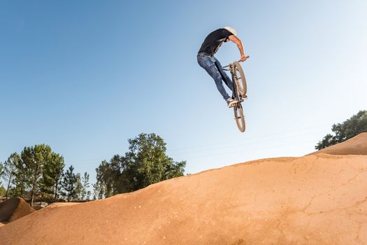 Bmx rider performing a look back at a dirt trail park.