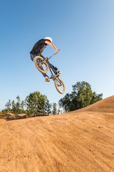 Bmx rider performing a look back at a dirt trail park.