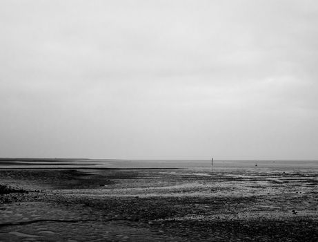 mono black and white texture pattern of mudflats and empty river and sky; England; UK