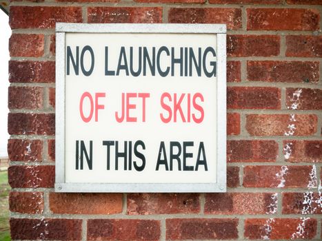 old retro sign lettering on wall saying no launching of jet skies in this area; England; UK