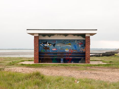 painted public roofed seats at seaside no people; England; UK