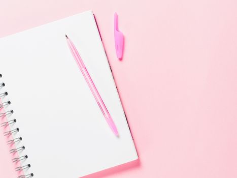 Top view of blank note paper with pen on pink pastel background. Copy space. Back to school and education concept