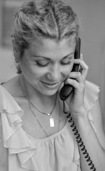 Smiling girl talking on wire telephone.
