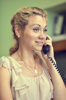Smiling girl talking on wire telephone.