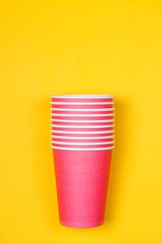 Stacks of pink paper cups on yellow background