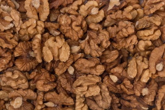 Closeup of big shelled walnuts pile, food background