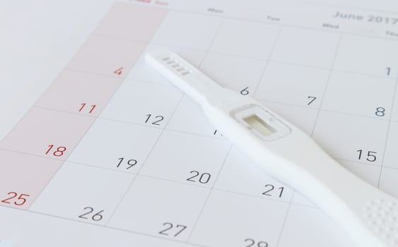 Pregnancy test on calendar background, health care concept