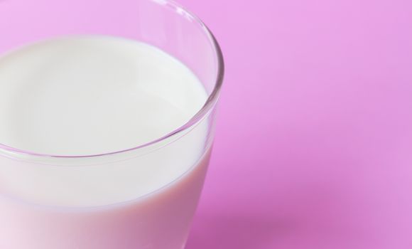 Closeup glass of milk on pink background, food and drink for healthy concept, selective and soft focus