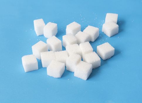 Sugar cubes on blue background, food and health care concept, selective focus