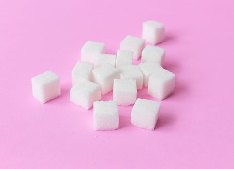 Sugar cubes on pink background, food and health care concept, selective focus