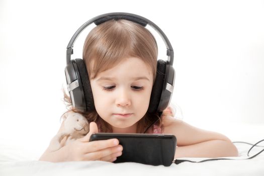 the little girl listens to music in earphones