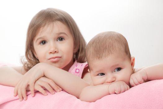 two little girls of the sisters lie on a pink plaid