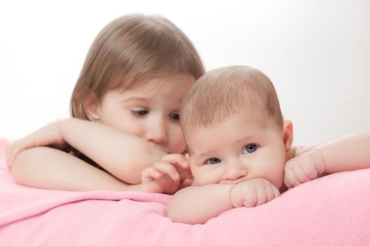 two little girls of the sisters lie on a pink plaid