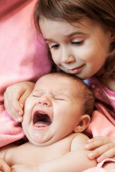 two little girls of the sisters lie on a pink plaid