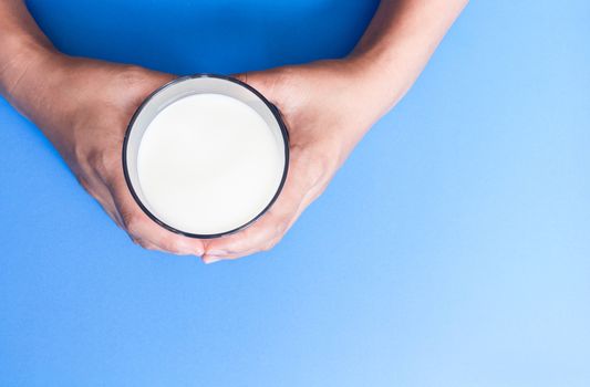 Hand holding glass of milk on blue background, food and drink for healthy concept