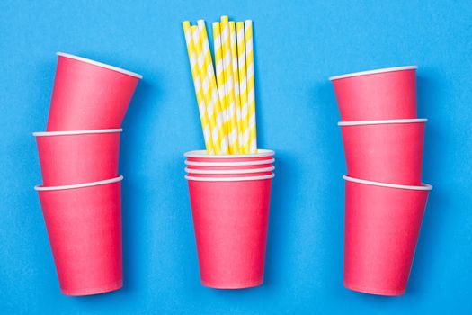 a bundle of multi-colored drinking straws in a paper Cup on a blue background. fashion minimal. flat lay