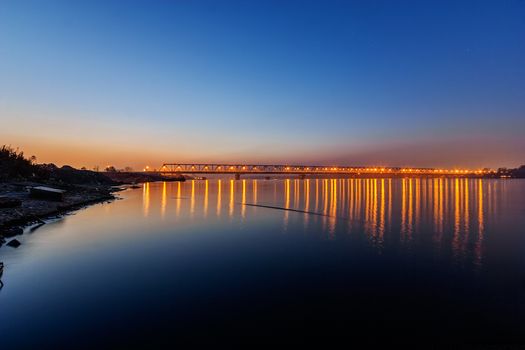 Steel bridge across river at night with artificial lightning