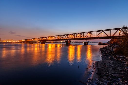 Steel bridge across river at night with artificial lightning