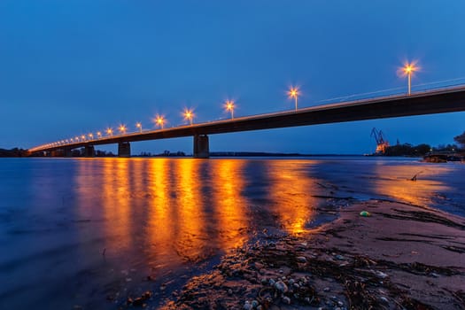 Steel bridge across river at night with artificial lightning