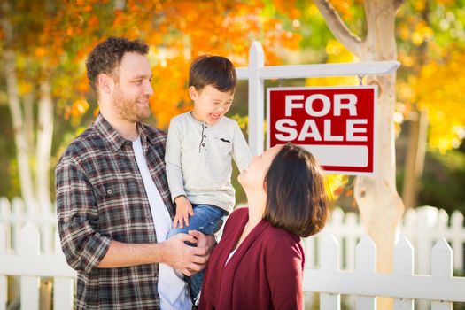 Young Mixed Race Chinese and Caucasian Family In Front of For Sale Real Estate Sign and Fall Yard.