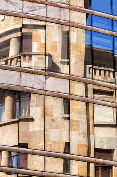 reflection of stone facade on modern glass facade