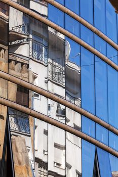 reflection of stone facade on modern glass facade